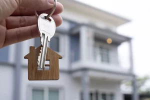A person holding a key in front of a house.